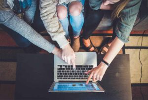 Mehrere Frauen zeigen auf Inhalte auf einem Laptop - Symbolbild für Gründe für WordPress